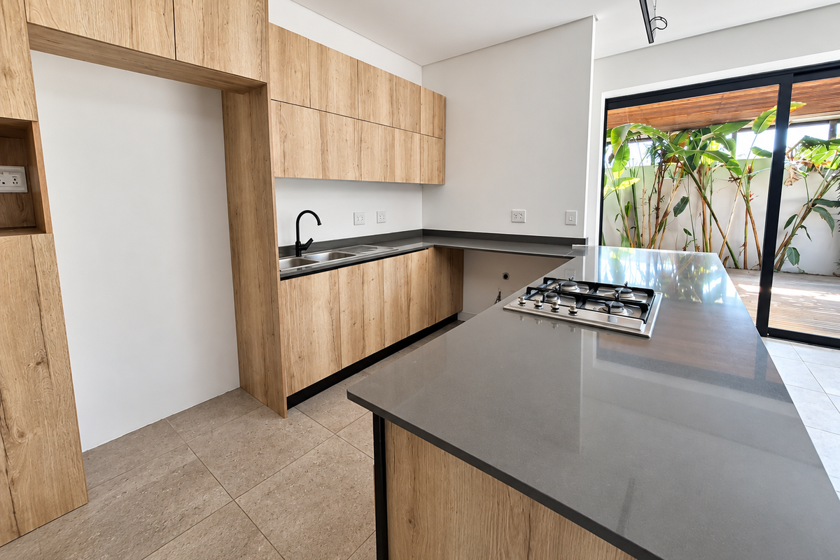Modern kitchen featuring light wood cabinetry, stone countertops, a central island with a gas hob, and direct access to an outdoor patio area.