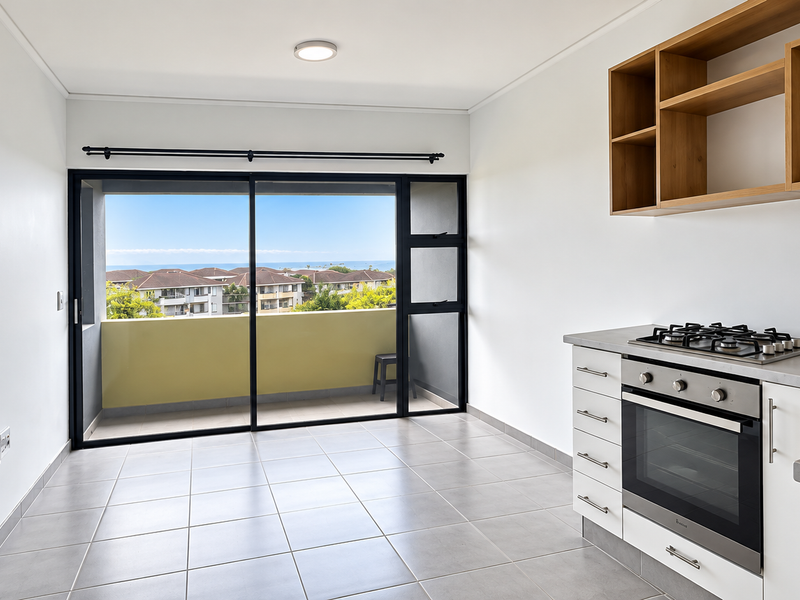 Modern open-plan kitchen and living area featuring tiled floors, built-in oven and hob, and direct access to a private balcony with scenic views.