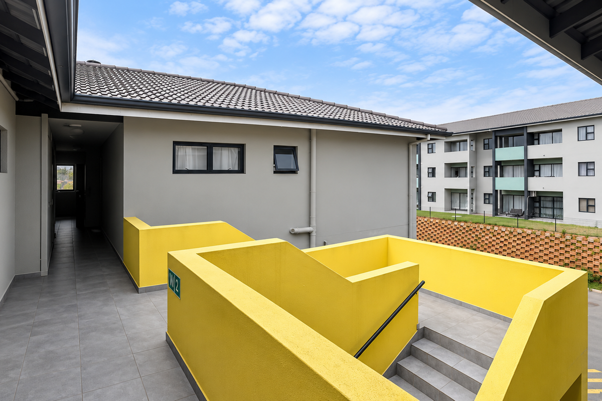 Exterior view of an apartment complex featuring a tiled staircase with a bright yellow balustrade and a covered walkway.