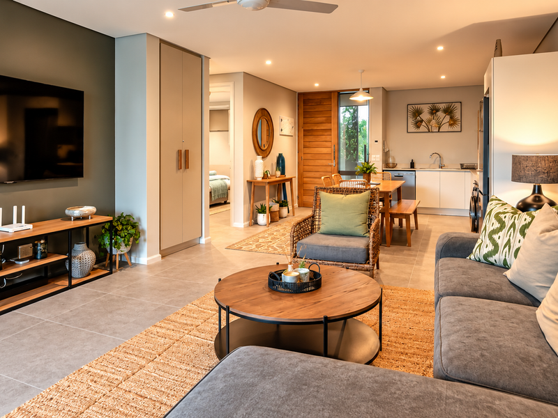 A modern open-plan living and kitchen area featuring tiled floors, recessed lighting, and a functional kitchen layout with integrated appliances.