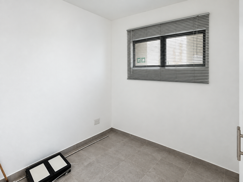 A clean, empty bedroom featuring neutral tiled flooring, white walls, and fitted venetian blinds, offering a blank canvas for personalization.