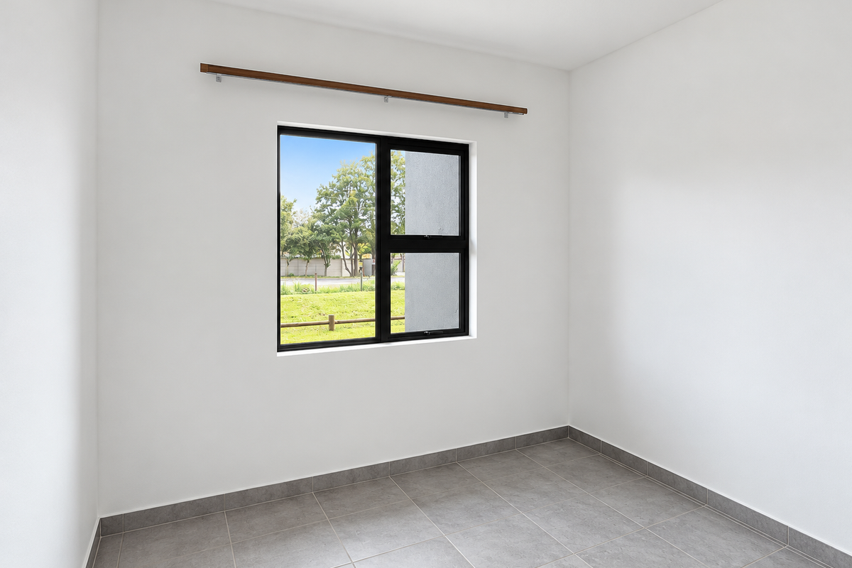 A bright, empty bedroom featuring neutral tiled flooring, white walls, and a black aluminium window frame with an integrated curtain rod.