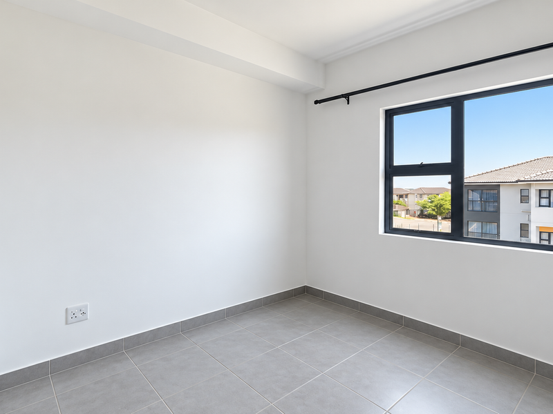 A bright, empty bedroom featuring neutral tiled flooring, clean white walls, and a modern aluminium-framed window with an installed curtain rod.