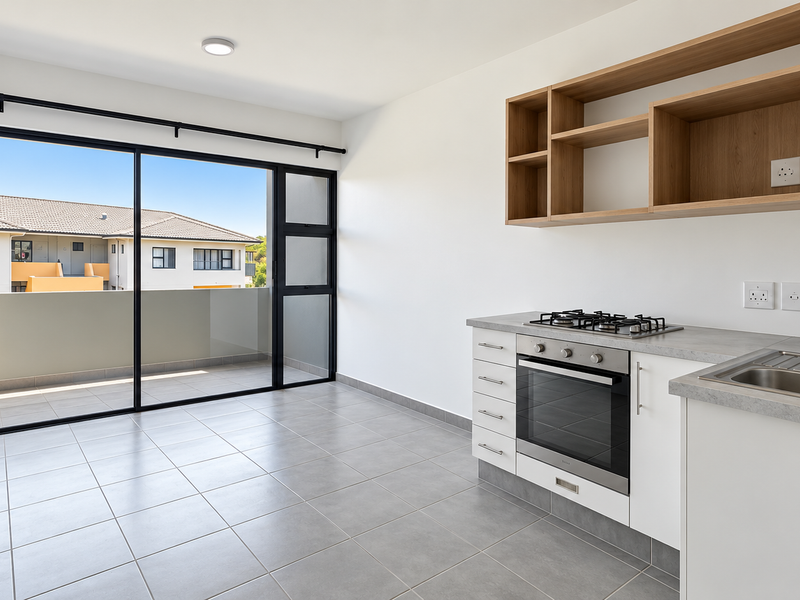 Modern open-plan kitchen featuring built-in oven, gas hob, and sleek cabinetry, leading out to a private balcony through large sliding glass doors.