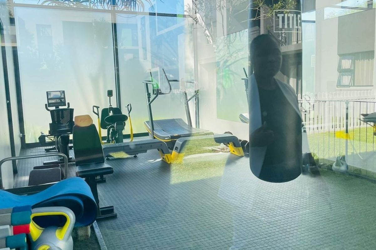 A modern, well-lit gym facility featuring durable rubberized flooring and floor-to-ceiling glass walls overlooking the outdoor area.