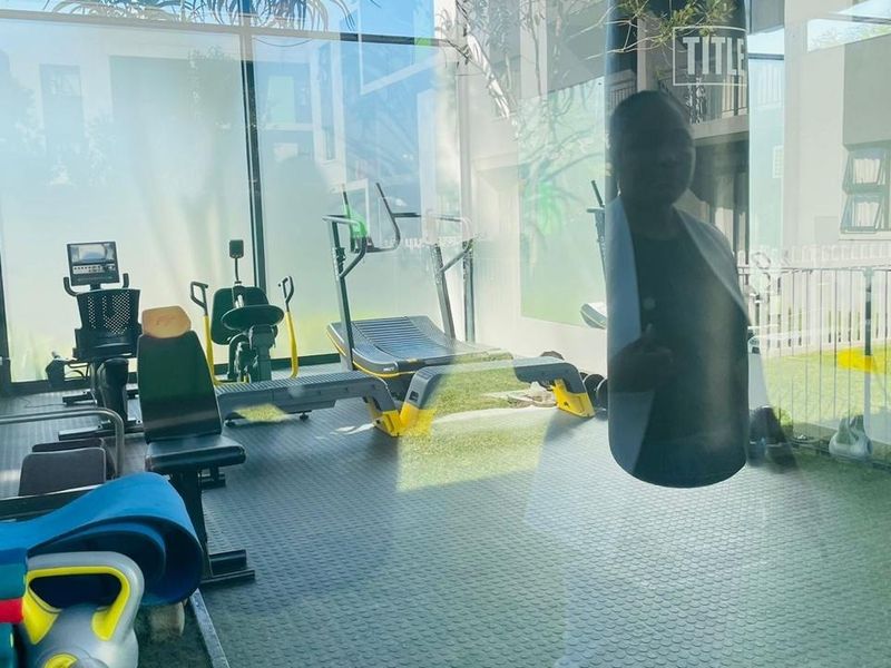 A modern, well-lit gym facility featuring durable rubberized flooring and floor-to-ceiling glass walls overlooking the outdoor area.