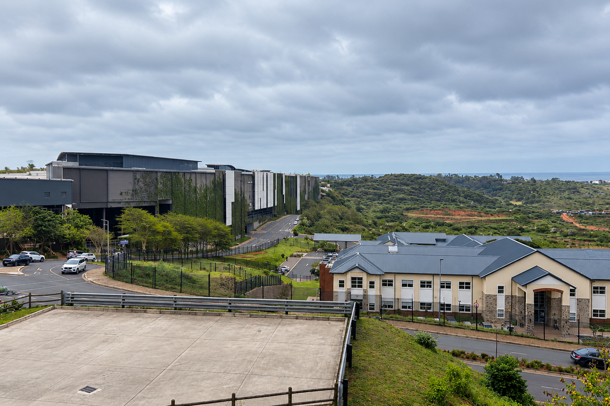 An elevated aerial view showing the surrounding estate infrastructure, including paved access roads, commercial building facades, and landscaped grounds under a cloudy sky.