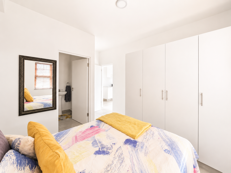 A bright bedroom featuring ample built-in cupboard storage and direct access to an en-suite bathroom.