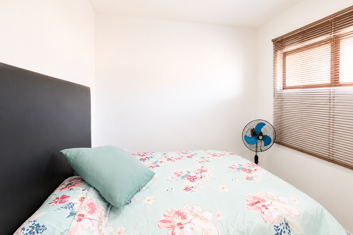 A compact bedroom featuring neutral walls and fitted venetian blinds, providing a simple and functional space.