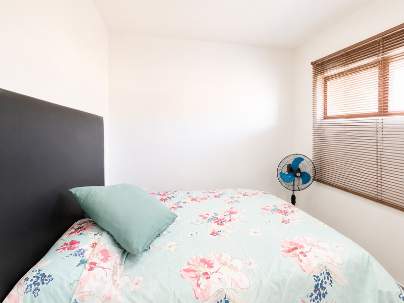 A compact bedroom featuring neutral walls and fitted venetian blinds, providing a simple and functional space.