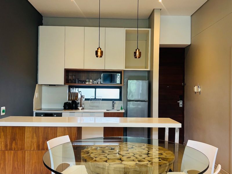 Modern open-plan kitchen featuring sleek built-in cabinetry, a functional island, and contemporary pendant lighting, seamlessly integrated into the living space.