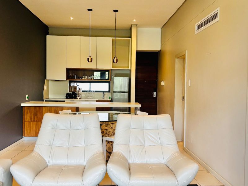 Modern open-plan living area featuring a sleek kitchen with built-in cabinetry, a central island, and ducted air conditioning, finished with neutral tones.