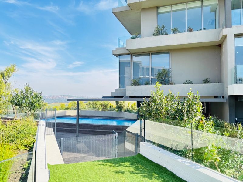 Modern apartment complex featuring a private swimming pool, timber decking, glass balustrades, and landscaped garden areas with scenic views.