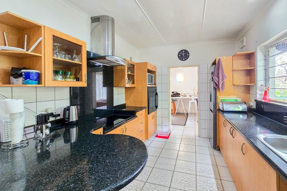 Functional kitchen featuring granite countertops, built-in cabinetry, integrated oven, and extractor fan with tiled flooring and backsplash.