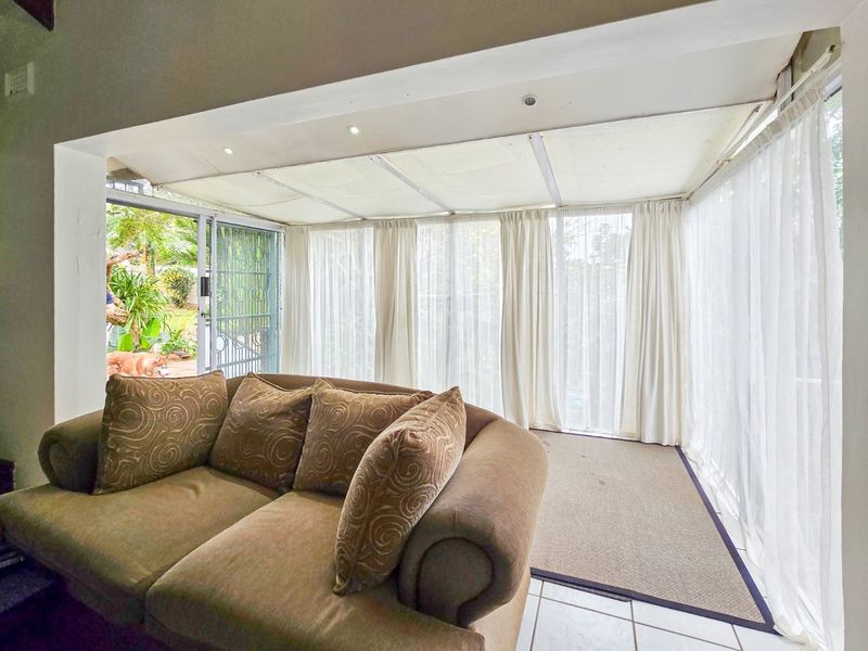 Enclosed patio area featuring tiled flooring, recessed ceiling lights, and large glass sliding doors providing access to the garden.