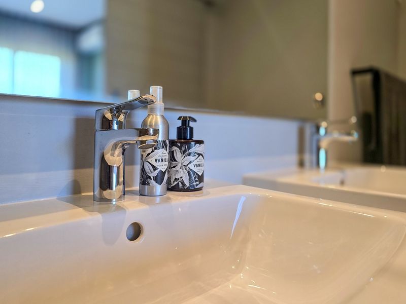 A modern bathroom featuring a double vanity with ceramic basins, chrome mixer taps, and a large wall-mounted mirror.