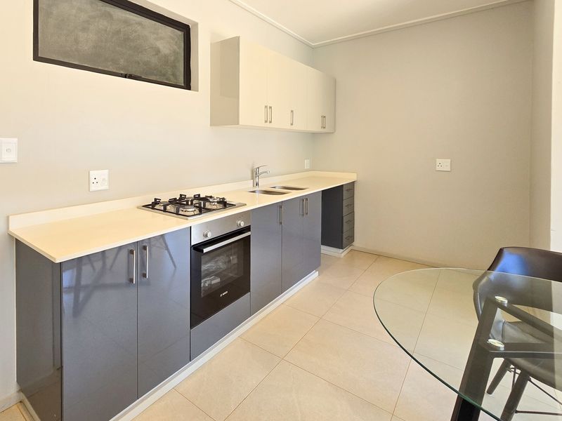 Modern kitchen featuring sleek grey and white cabinetry, stone countertops, a built-in gas hob, and an integrated oven.