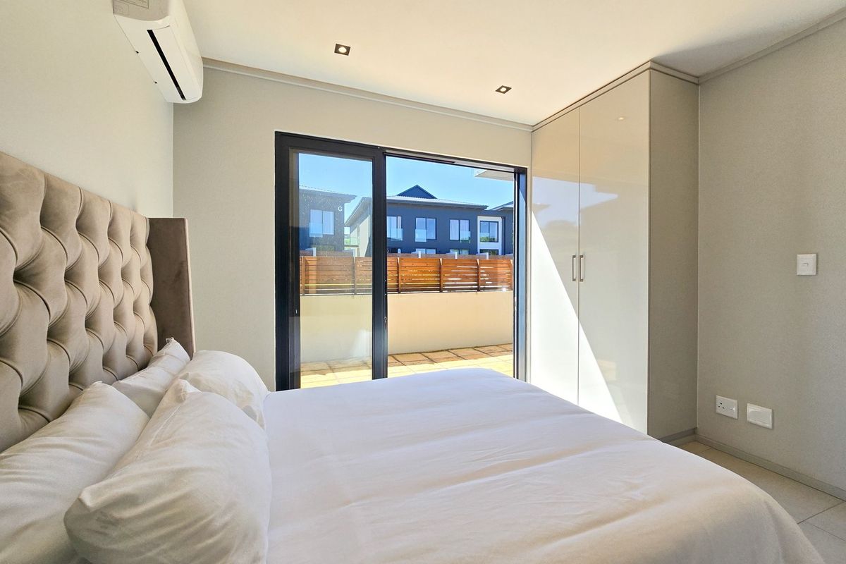 Modern bedroom featuring built-in cupboards, tiled flooring, recessed lighting, and a sliding glass door providing direct access to an outdoor patio area.