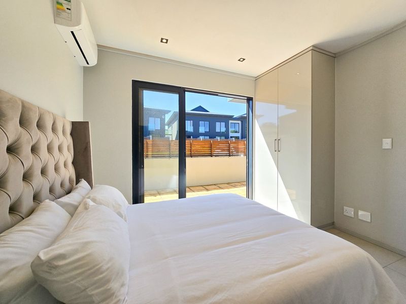 Modern bedroom featuring built-in cupboards, tiled flooring, recessed lighting, and a sliding glass door providing direct access to an outdoor patio area.