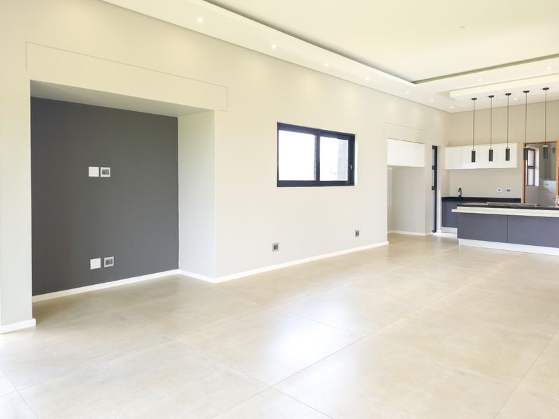 Spacious open-plan living and kitchen area featuring modern tiled floors, recessed ceiling lighting, and a contemporary kitchen island with built-in cabinetry.