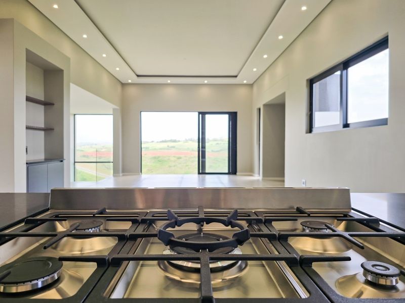 Modern open-plan living area featuring a built-in gas cooktop, recessed ceiling lighting, and large sliding doors with scenic views.
