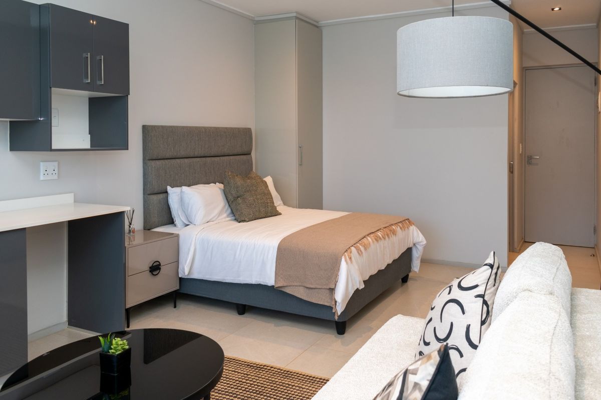 A modern, well-maintained bedroom featuring neutral tones, built-in cabinetry, and tiled flooring, offering a clean and functional living space.