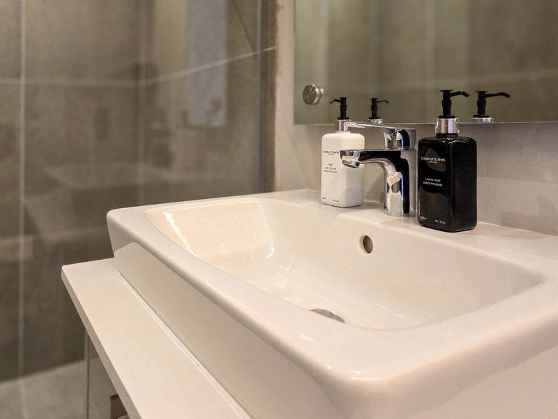 A modern bathroom featuring a clean ceramic basin with a chrome mixer tap and a large wall-mounted mirror.