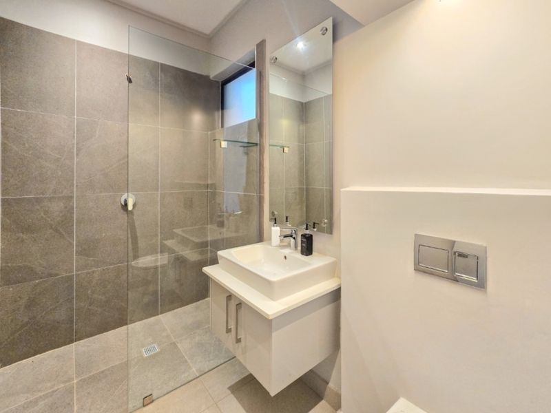 Modern bathroom featuring a walk-in shower with glass screen, wall-mounted vanity with basin, and a concealed cistern flush plate.