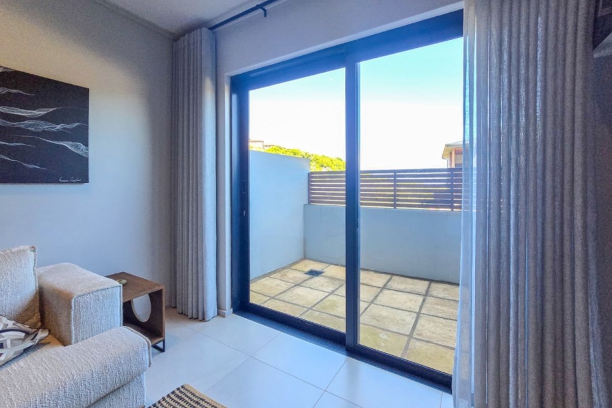 A bright living area featuring large sliding glass doors that provide seamless access to a private outdoor patio space.