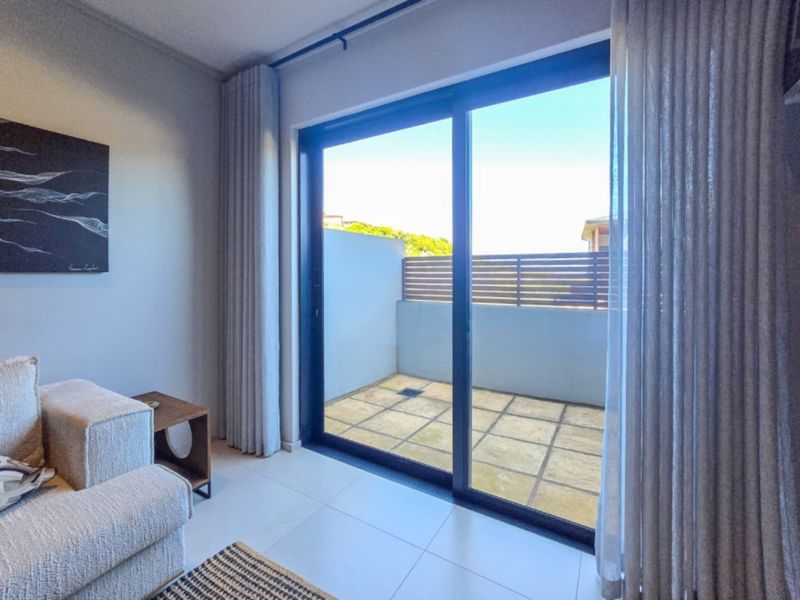 A bright living area featuring large sliding glass doors that provide seamless access to a private outdoor patio space.