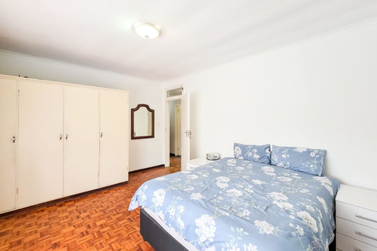 A bedroom featuring classic parquet flooring and built-in cupboards, offering a neutral canvas for potential interior updates.