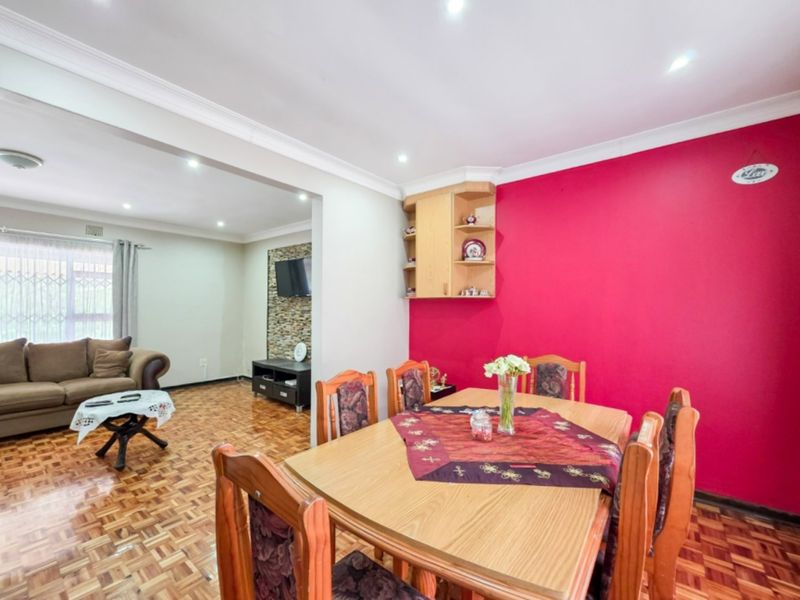 Open-plan living and dining area featuring parquet flooring, recessed lighting, and a stone feature wall, creating a connected and functional living space.