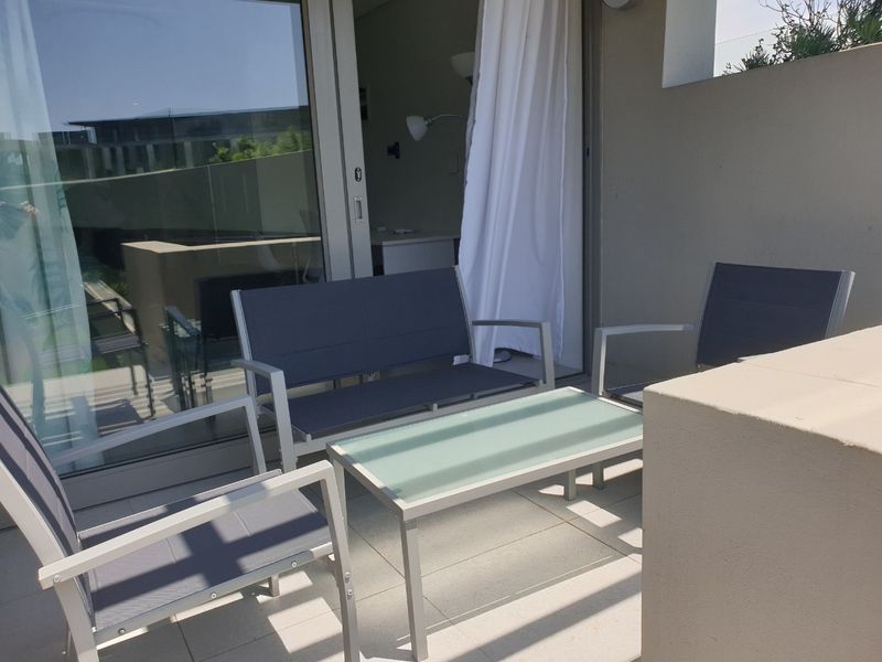 A private balcony featuring tiled flooring, a masonry balustrade, and large sliding glass doors providing seamless access to the interior living space.