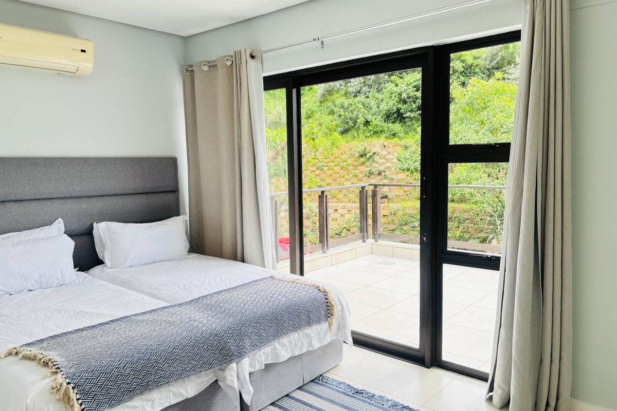 Bright bedroom featuring tiled flooring, an air conditioning unit, and large sliding glass doors providing direct access to a private balcony.