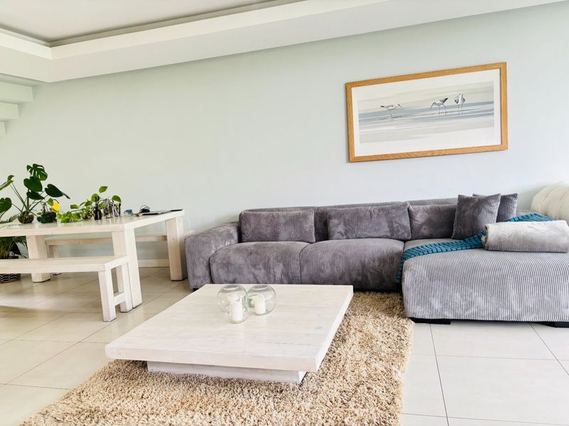 A bright and spacious living room featuring neutral tiled flooring and a modern recessed ceiling design, creating a comfortable and inviting atmosphere.