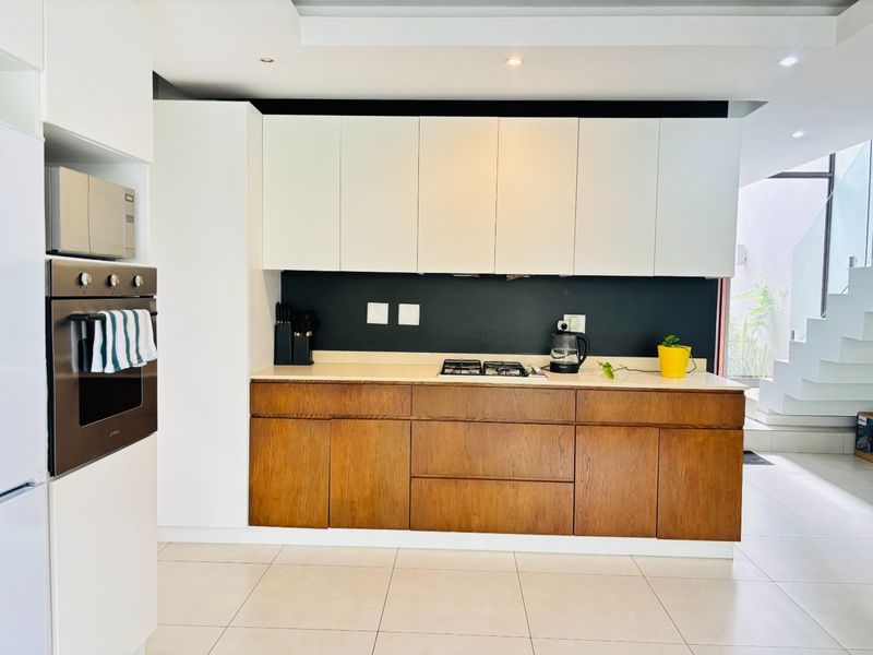 Modern kitchen featuring a two-tone cabinetry design, built-in oven, gas hob, and stone countertops, offering a clean and contemporary aesthetic.