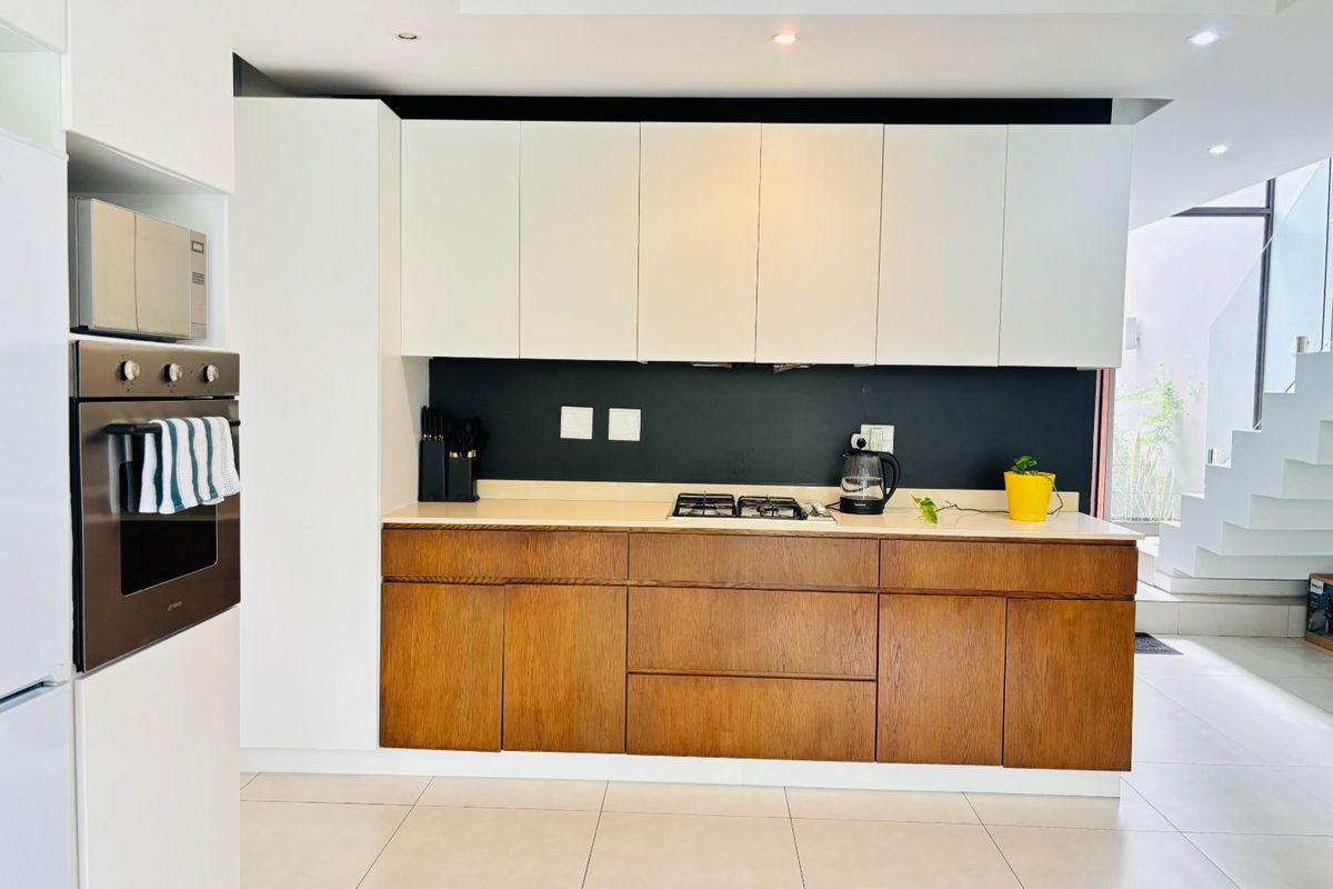 Modern kitchen featuring a two-tone cabinetry design, built-in oven, gas hob, and stone countertops, offering a clean and contemporary aesthetic.