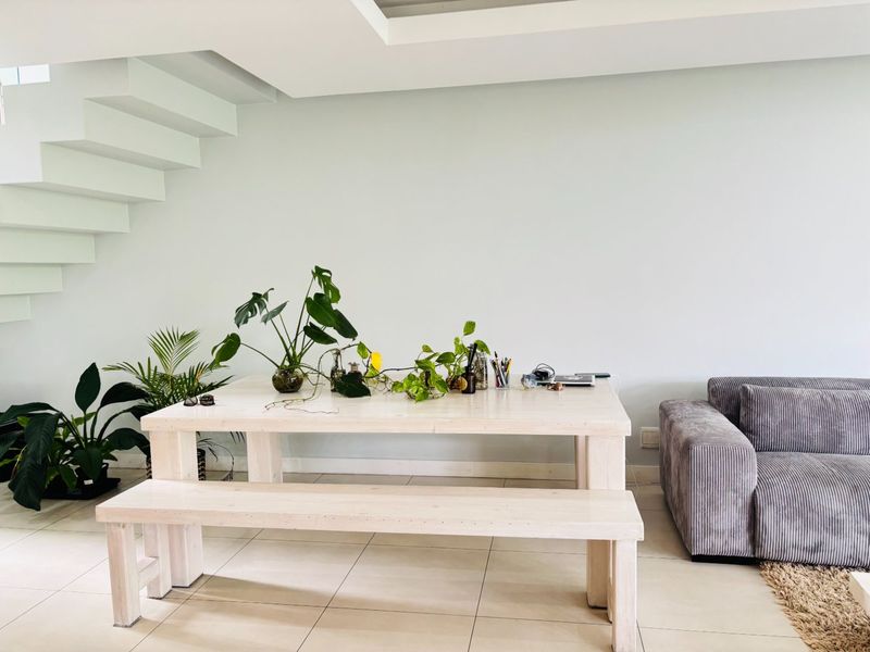 A bright living area featuring modern tiled flooring and a striking white floating staircase, creating an open and contemporary atmosphere.