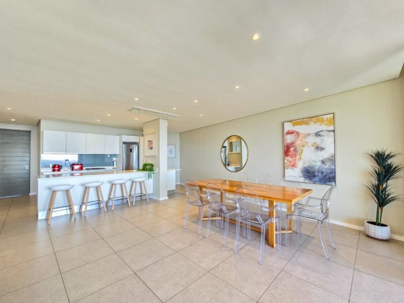 Spacious open-plan living and dining area featuring a modern kitchen with a breakfast island, tiled floors, and recessed lighting throughout.