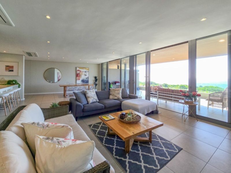 Spacious open-plan living area featuring large format floor tiles, recessed lighting, and seamless flow to a covered patio through expansive sliding glass doors.