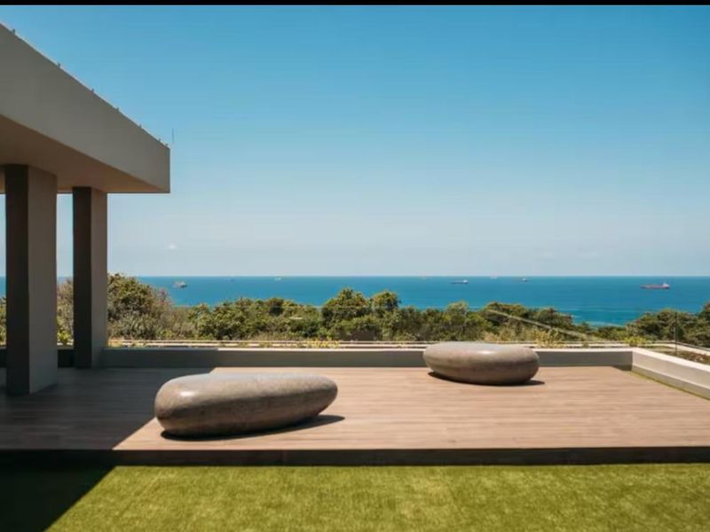 A spacious outdoor patio featuring timber decking and a glass balustrade, offering expansive ocean views.