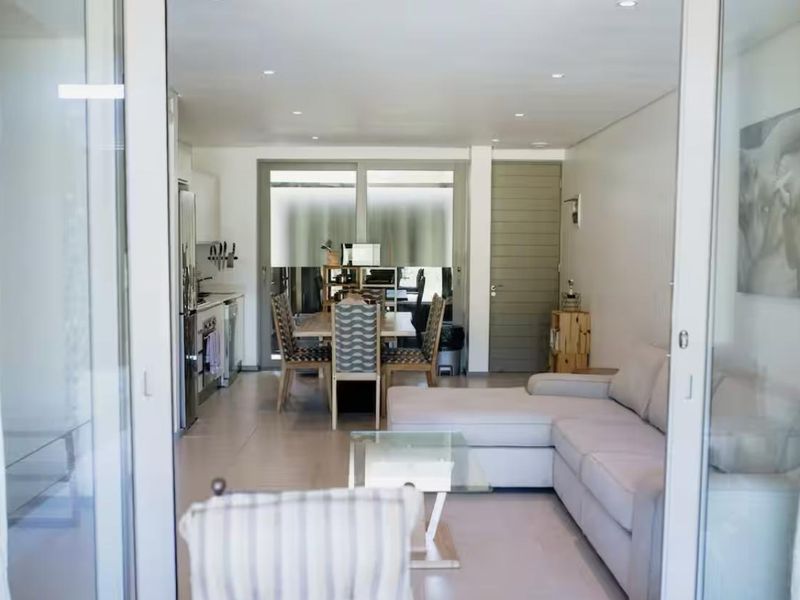 An open-plan living and kitchen area featuring tiled floors, recessed lighting, and large sliding glass doors that provide access to the outdoor space.
