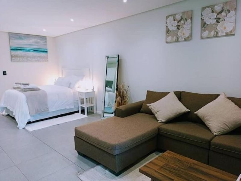 An open-plan studio apartment featuring neutral tiled flooring and recessed downlighting, creating a bright and functional living and sleeping space.