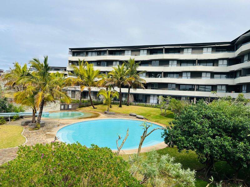 A well-maintained apartment complex featuring a central swimming pool, landscaped garden areas, and multi-story residential units with private balconies.