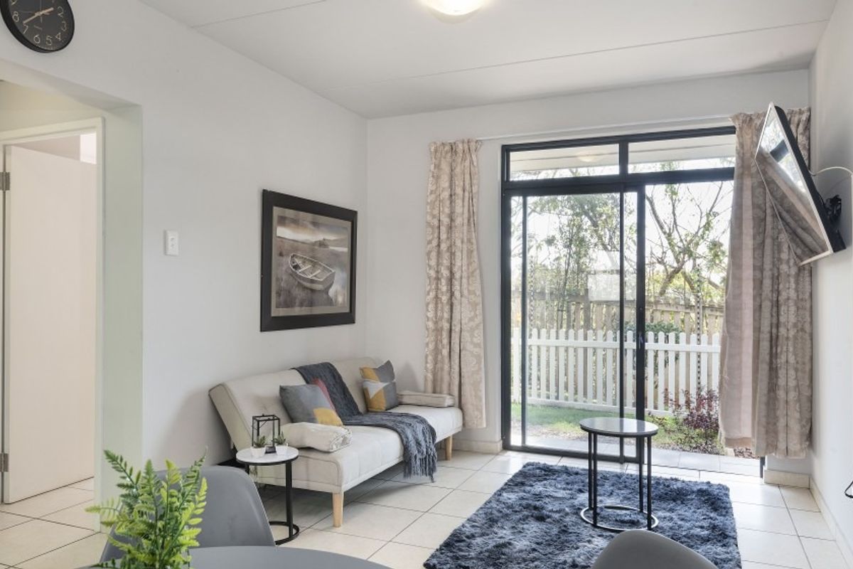 A bright living room featuring tiled flooring and a large sliding glass door providing direct access to the outdoor area.