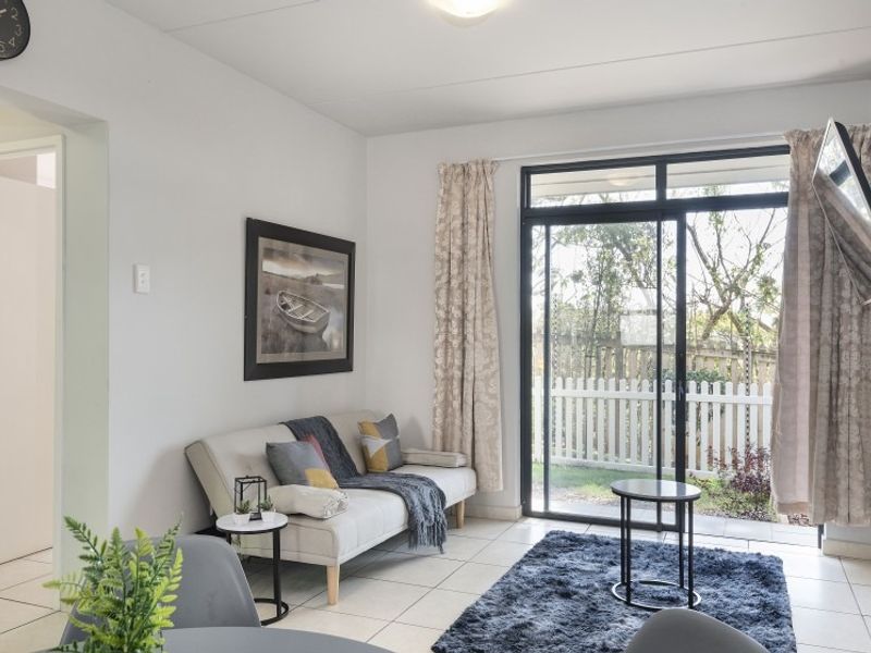 A bright living room featuring tiled flooring and a large sliding glass door providing direct access to the outdoor area.