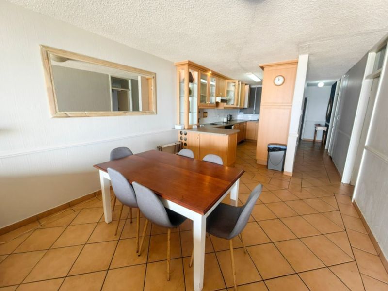 Open plan living and dining area featuring ceramic tiled flooring and a functional kitchen with wooden cabinetry and laminate countertops.