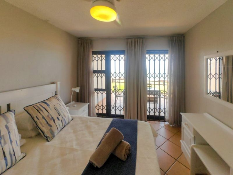 A bedroom featuring tiled flooring, a ceiling fan, and sliding glass doors with security gates leading to an outdoor patio area.