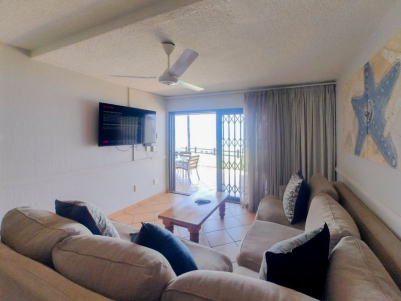 A comfortable living room featuring tiled flooring, a ceiling fan, and direct access to an outdoor patio through a sliding glass door.