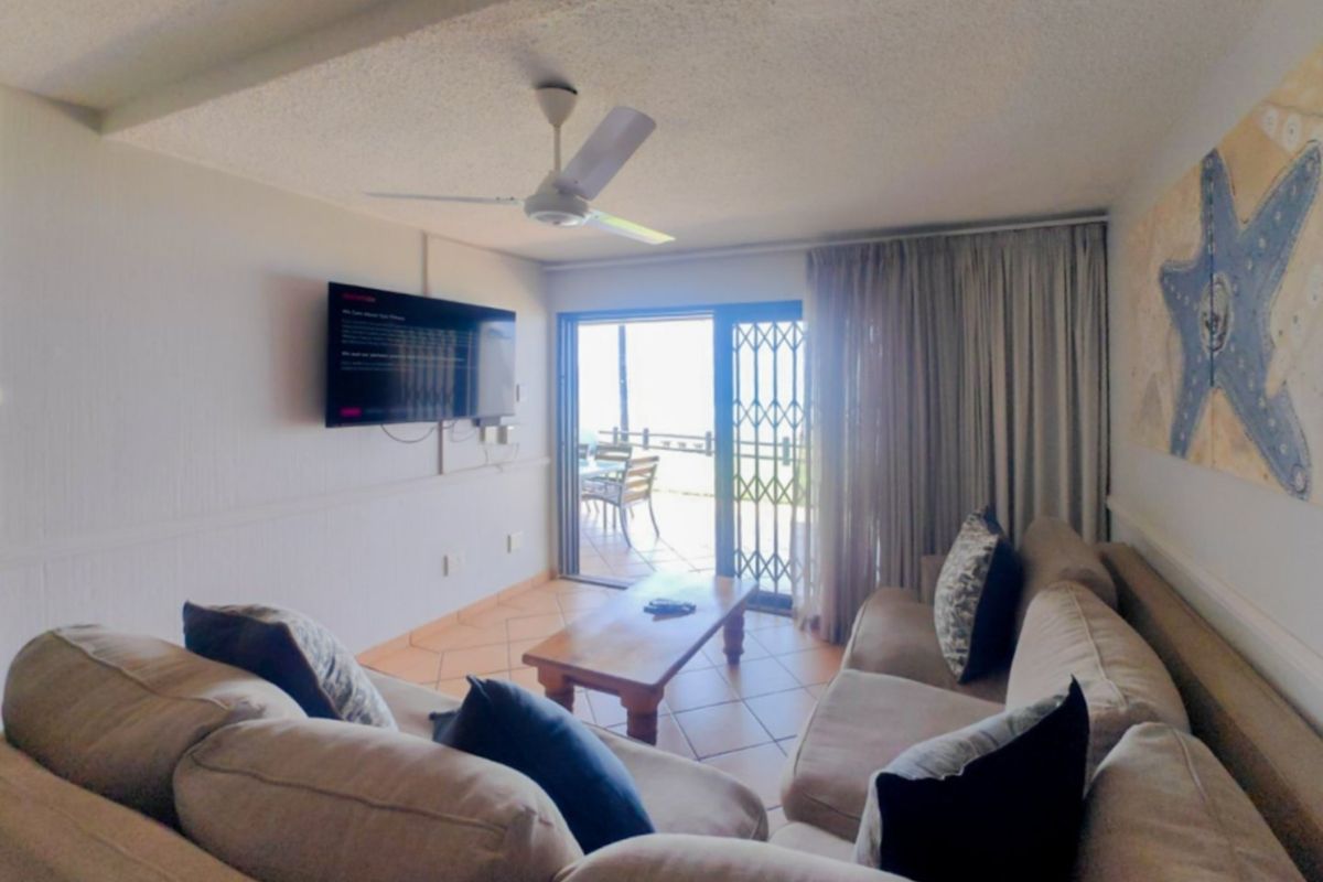 A comfortable living room featuring tiled flooring, a ceiling fan, and direct access to an outdoor patio through a sliding glass door.